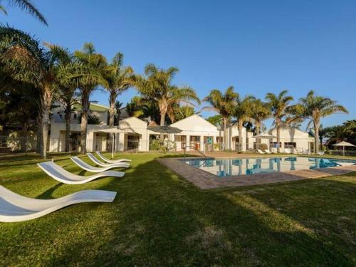 a group of white lounge chairs by a swimming pool at Castleton Unit 73 Plettenberg Bay in Plettenberg Bay