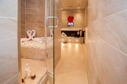 a glass shower in a bathroom with a bed in a room at Windermere Boutique Hotel Spa Suites & Hot Tubs in Windermere