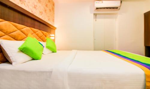 a bedroom with a white bed with green and white pillows at Treebo Arvind Residency in Mumbai