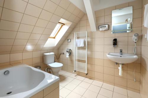 a bathroom with a tub and a toilet and a sink at Pension U Tří sedláků in České Budějovice