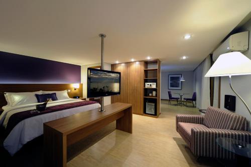 a bedroom with a large bed and a chair at Radisson Hotel Belém in Belém