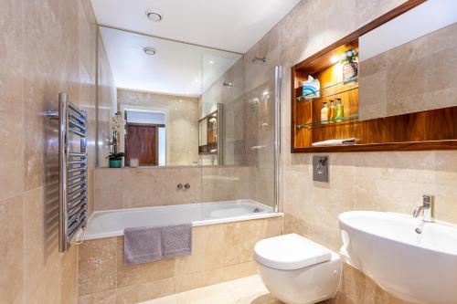 a bathroom with a tub and a toilet and a sink at Esquire Media City in Manchester