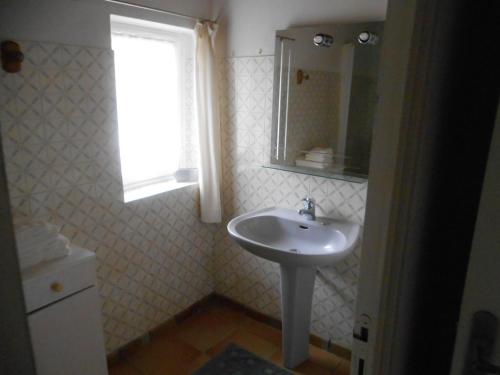ein weißes Bad mit einem Waschbecken und einem Fenster in der Unterkunft Ty Coz in Saint-Ségal