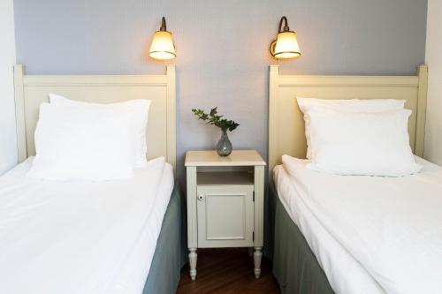 two beds with white pillows and a nightstand between them at Best Western Eurostop Orebro in Örebro