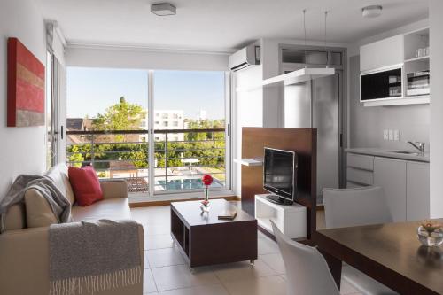a living room with a couch and a table and a television at Real Colonia Hotel & Suites in Colonia del Sacramento