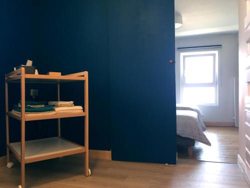 une chambre avec un mur bleu et une étagère à livres dans l'établissement "Le petit Moulinsard", à Bernay