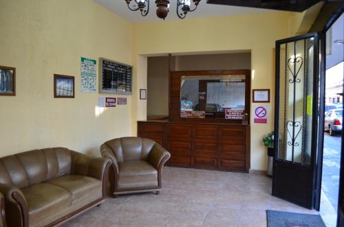 una sala de espera con 2 sillas de cuero y un espejo en Hotel Del Centro, en Puebla