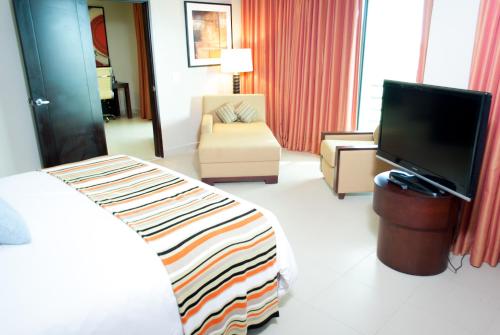 a hotel room with a bed and a flat screen tv at Summit Rainforest Golf Resort & All Inclusive in Paraíso