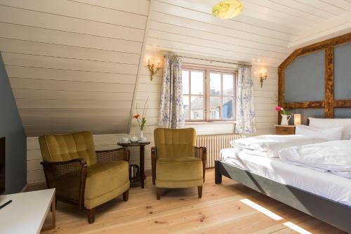 a bedroom with a bed and two chairs and a window at Gutshaus Lexow in Lexow