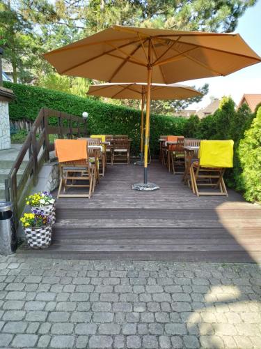 una terrazza in legno con tavoli, sedie e ombrellone di Krakowska 39 a Kazimierz Dolny