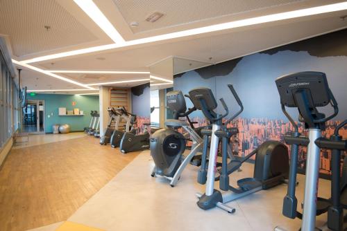 a gym with tread machines and a wall with a painting at Novotel São Paulo Berrini in Sao Paulo