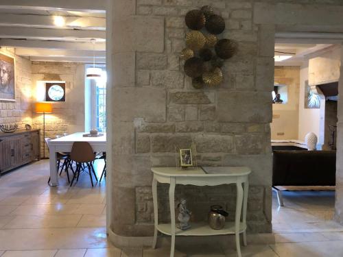 ein Wohnzimmer mit einem Tisch und einer Steinmauer in der Unterkunft Villa Donna jacuzzi jardin billard centre la Brèche in Niort