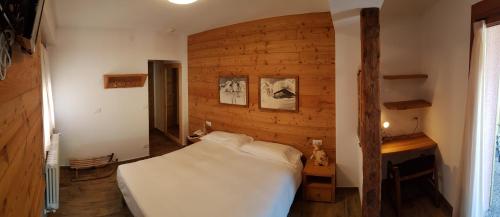 una camera con un letto bianco e una parete in legno di Albergo Soldanella a Madesimo