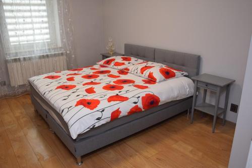 - une chambre avec un lit orné de fleurs rouges dans l'établissement APARTAMENTY Kudowa Zdrój - Słone, à Kudowa-Zdrój