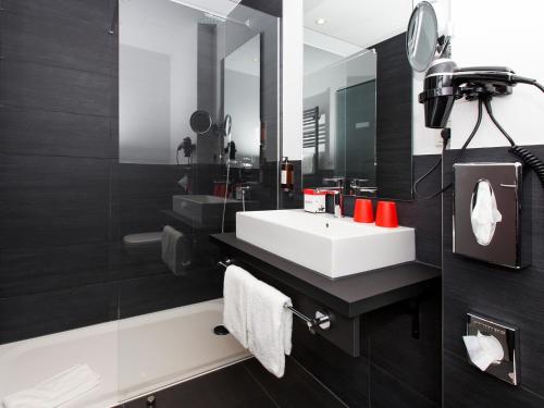 een badkamer met een witte wastafel en een spiegel bij DORMERO Hotel Salzgitter in Salzgitter