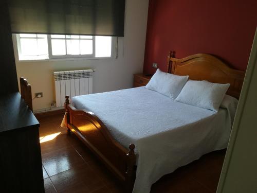 a bedroom with a bed with white sheets and a window at Pensión Restaurante Casa Camiño II in Palas de Rei