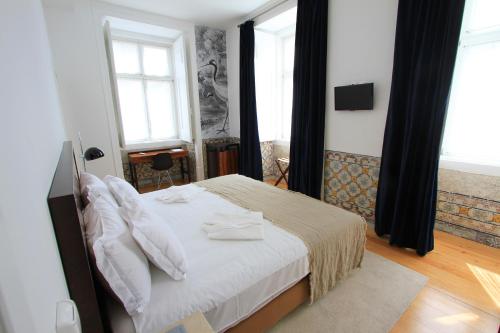 a bedroom with a bed and two windows at Lisboa Prata Boutique Hotel in Lisbon