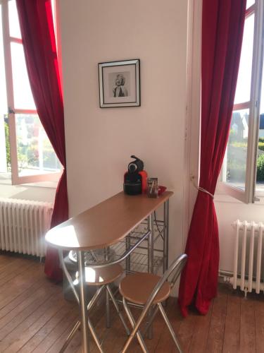 - une table et des chaises dans une chambre dotée de rideaux rouges dans l'établissement Les chambres d’hôtes de Rânes, à Rânes