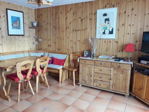 comedor con paredes de madera, mesa y sillas en Le Panda en Les Carroz d'Araches