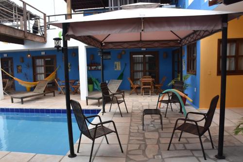 eine Terrasse mit Stühlen und einem Sonnenschirm neben einem Pool in der Unterkunft Pousada Amigos do Vento in Touros