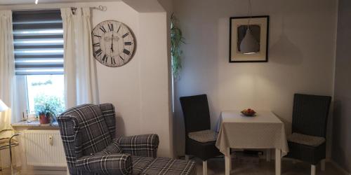 a living room with a table and chairs and a clock at Dorfstraße 21 Ferienwohnung 3 in Schwielowsee