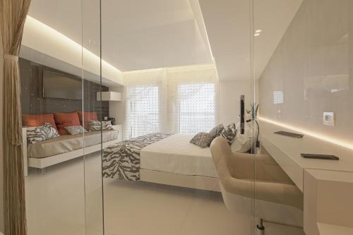 a white bedroom with a bed and a glass wall at Hedoné Design Experience B&B in Agrigento