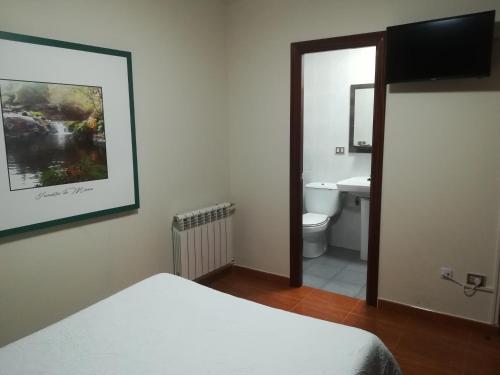 a bedroom with a bed and a bathroom with a sink at Pensión Restaurante Casa Camiño II in Palas de Rei 