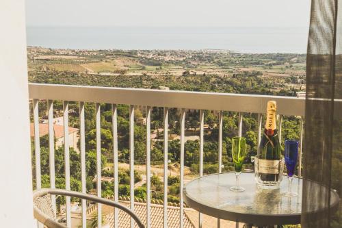 a table with a bottle of wine on a balcony at Hedoné Design Experience B&B in Agrigento