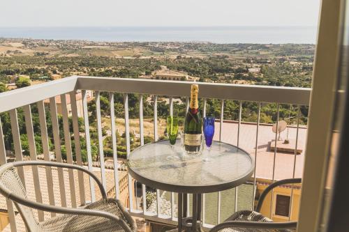 a glass table with a bottle of wine on a balcony at Hedoné Design Experience B&B in Agrigento