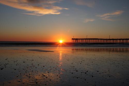 a sunset on the beach with a pier in the background at Shoreline Inn...on the beach in Cayucos