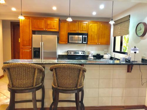 a kitchen with a counter and two bar chairs at Monte Carlo Luxury Condominiums in Jacó