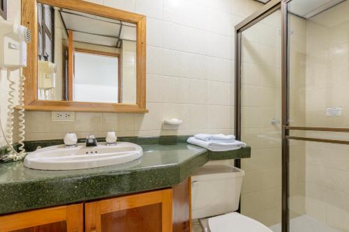 
a bathroom with a sink, toilet and mirror at Hotel Florida Inn in Medellín
