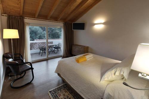 a bedroom with a bed and a chair and a balcony at Quinta do Chocalhinho Agroturismo & SPA in Odemira