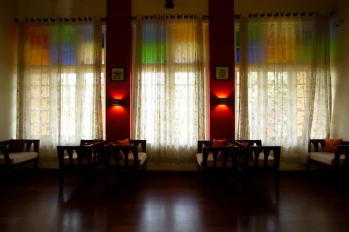a dining room with tables and chairs in front of windows at Tea Bungalow in Cochin