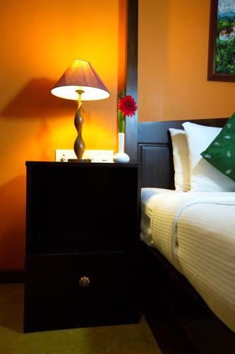 a bedroom with a bed and a lamp on a night stand at Tea Bungalow in Cochin