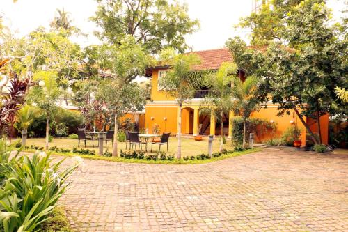 a yellow house with a brick driveway in front of it at Tea Bungalow in Cochin