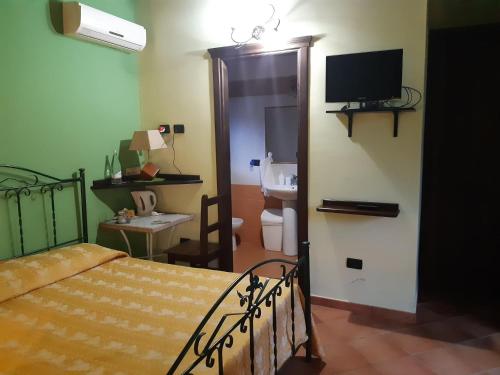 een slaapkamer met een bed en een badkamer met een televisie bij Agriturismo Il Pozzo Antico in Mascali