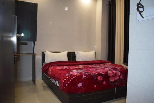 a bedroom with a bed with red sheets and pillows at Hotel Star Light in Amritsar