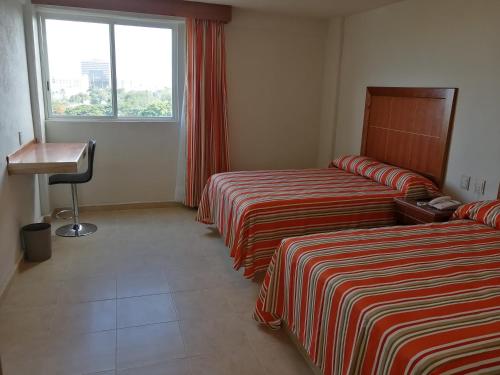 a hotel room with two beds and a window at Misol-Ha Hotel M&eacute;rida in M&eacute;rida