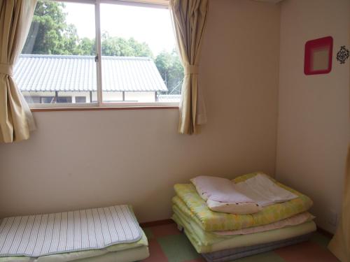 a room with two beds in front of a window at Kumamoto Guesthouse Minami Aso Little Asia in Minami Aso