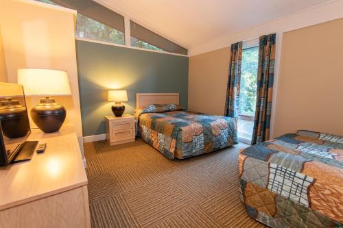 a bedroom with two beds and a desk and a tv at Kentucky Dam Village State Resort Park in Gilbertsville
