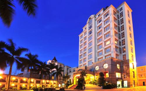 a large building with palm trees in front of it at Camela Hotel & Resort in Hai Phong