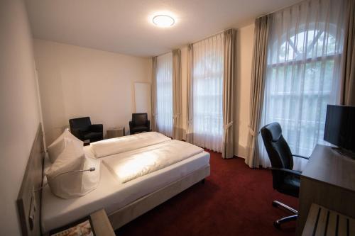 a hotel room with a bed and chairs and a window at Altes Landhaus in Lingen