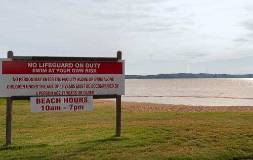 a sign in front of a beach with the water at Kentucky Dam Village State Resort Park in Gilbertsville
