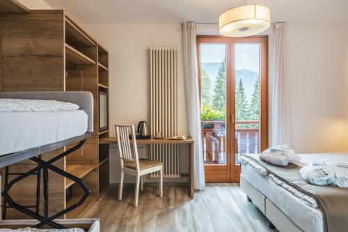 a bedroom with a bed and a desk with a chair at Hotel Folgarida in Folgarida