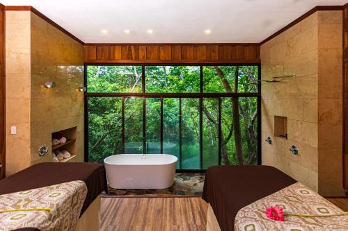 a bathroom with two beds and a tub in front of a window at Hacienda Guachipelin Volcano Ranch Hotel & Hot Springs in Liberia