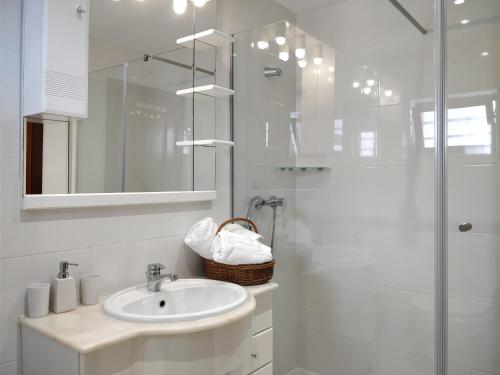 a white bathroom with a sink and a shower at Oceanides Beachfront Apartments in Quarteira