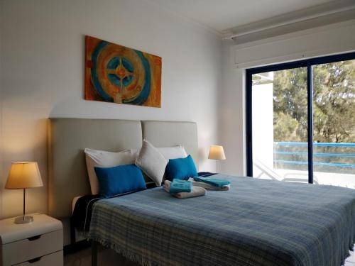 a bedroom with a bed with blue pillows and a window at Oceanides Beachfront Apartments in Quarteira