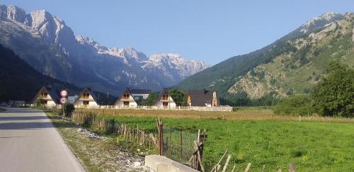 a road next to a field with mountains in the background at Bujtinat e lugines Valbone in Valbonë