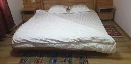 Una cama con sábanas blancas y almohadas. en Bujtinat e lugines Valbone, en Valbonë